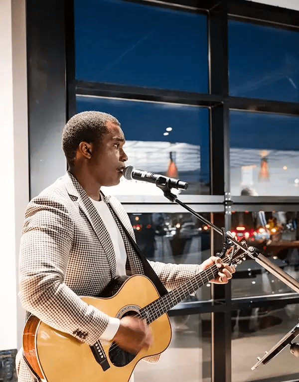 Man in sports coat singing and playing guitar